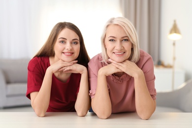 Photo of Portrait of mature woman and her daughter at table indoors