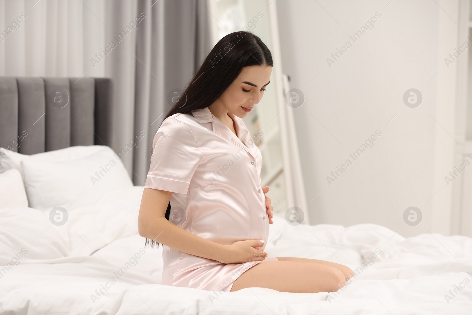 Photo of Pregnant young woman on bed at home