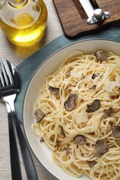 Photo of Tasty spaghetti with truffle served on wooden table, flat lay