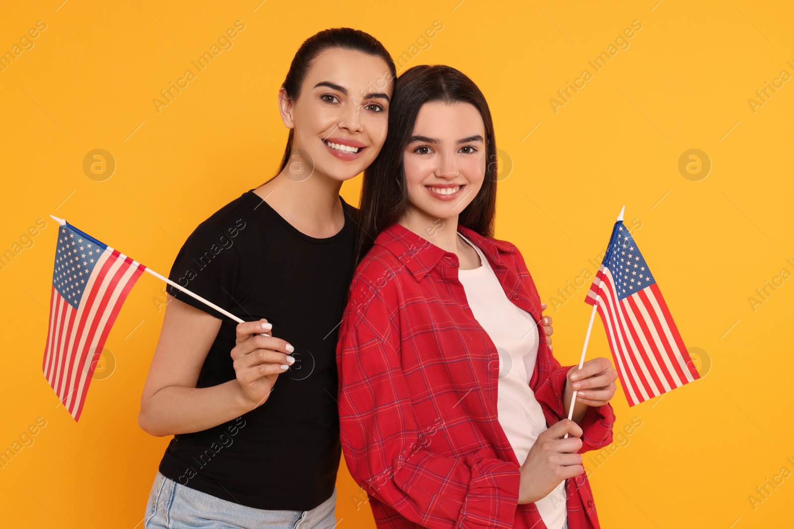 Photo of 4th of July - Independence Day of USA. Happy woman and her daughter with American flags on yellow background