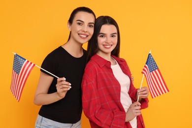 4th of July - Independence Day of USA. Happy woman and her daughter with American flags on yellow background