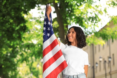 Photo of Happy young woman with American flag on sunny day