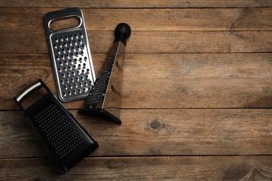 Photo of Different modern graters on wooden table, flat lay. Space for text