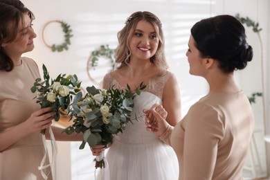 Photo of Happy bride and her bridesmaids with beautiful bouquets at home