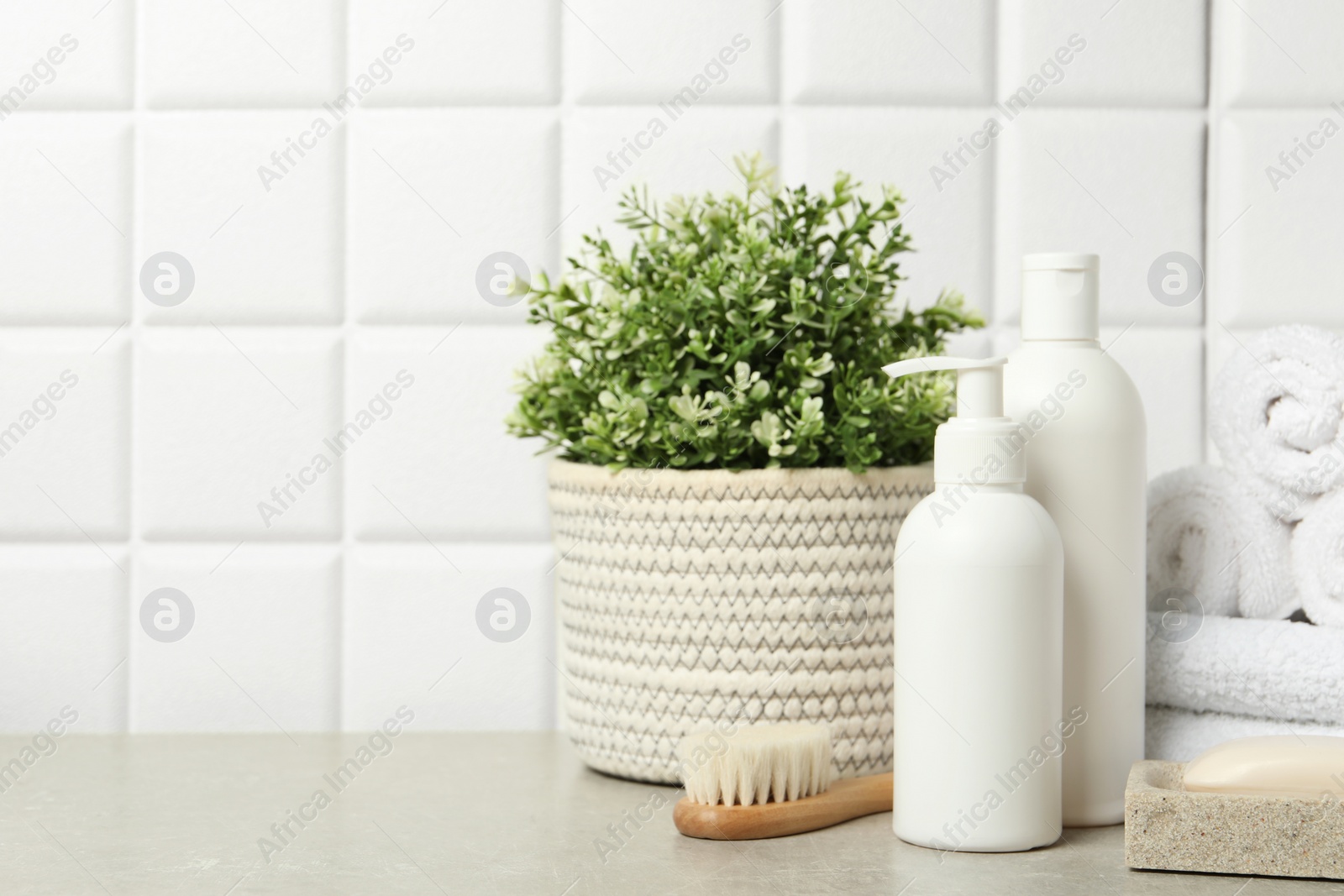 Photo of Different bath accessories and personal care products on gray table near white tiled wall, space for text