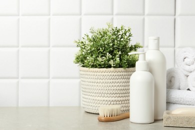 Different bath accessories and personal care products on gray table near white tiled wall, space for text