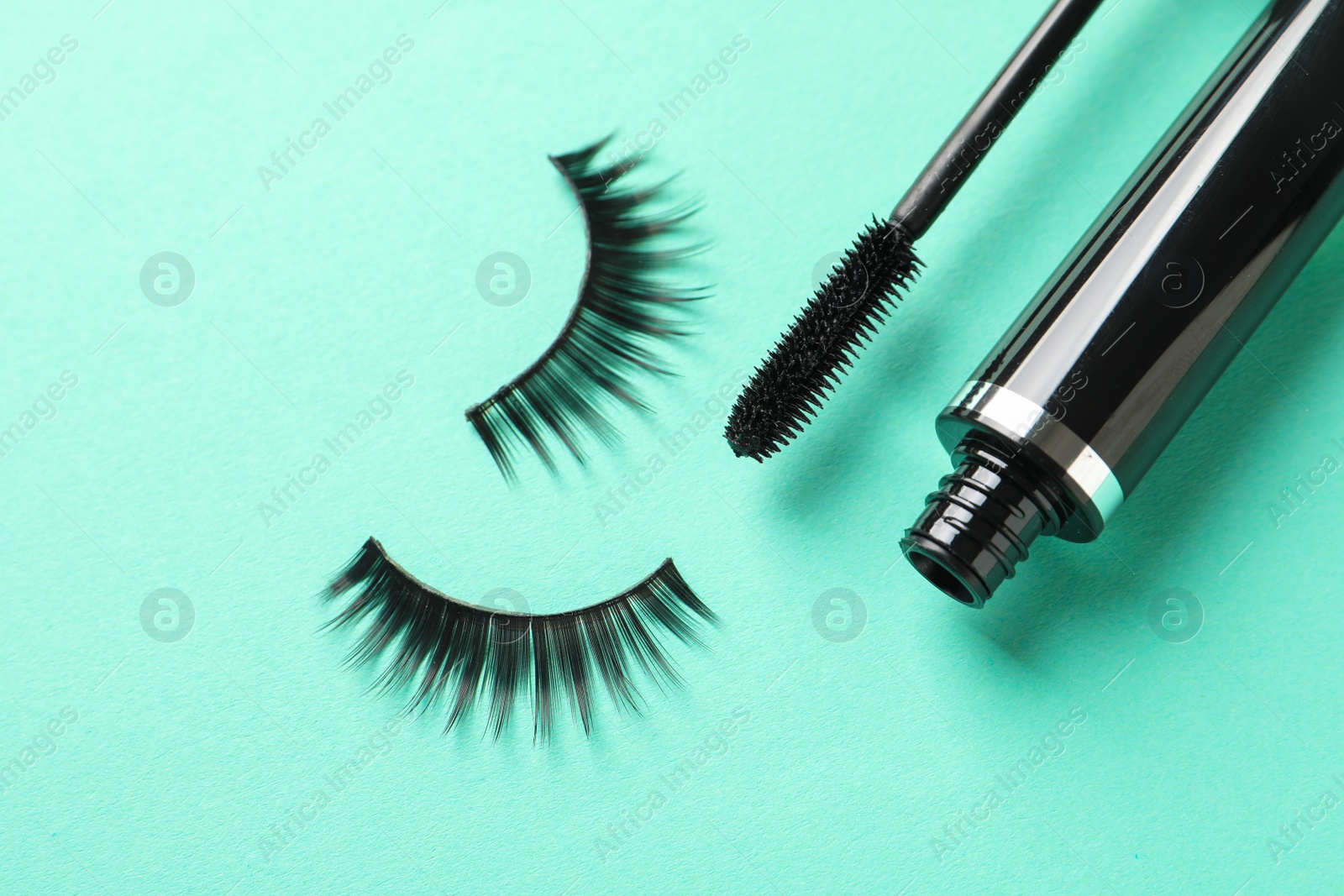 Photo of False eyelashes and mascara on turquoise background, flat lay