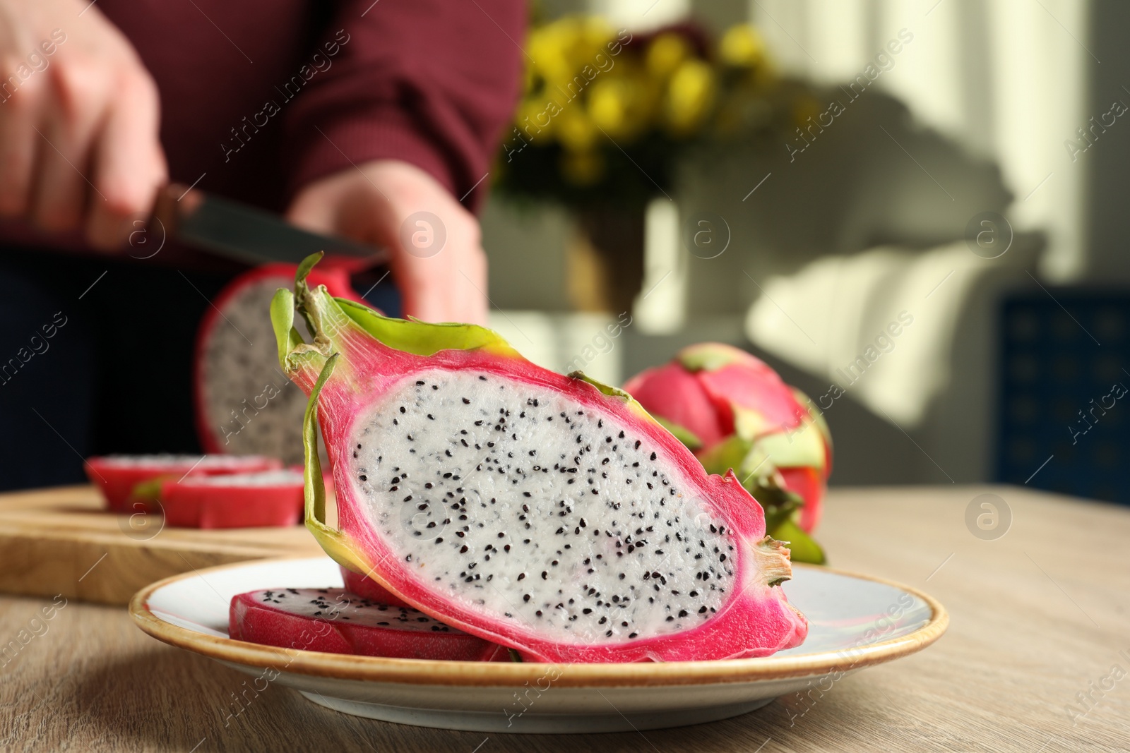 Photo of Plate with delicious cut white pitahaya fruit on wooden table indoors, closeup
