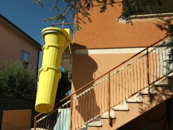 Photo of Building with yellow rubble chute outdoors on sunny day