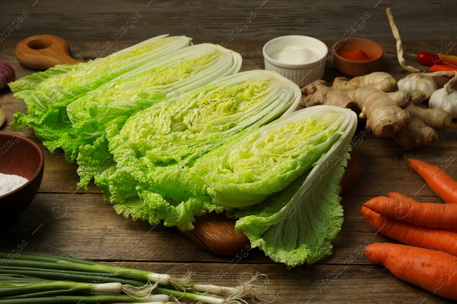 Photo of Cut fresh ripe Chinese cabbages and ingredients on wooden table