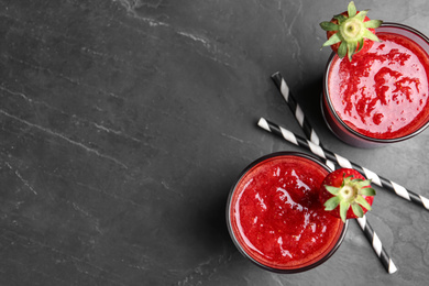 Photo of Tasty strawberry smoothies in glasses on black table, flat lay. Space for text