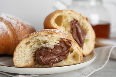 Photo of Tasty croissants with chocolate and sugar powder on plate, closeup
