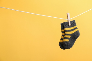 Photo of Small socks hanging on washing line against color background, space for text. Baby accessories