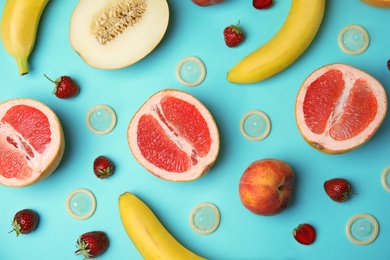 Photo of Flat lay composition with condoms and exotic fruits on turquoise background. Erotic concept