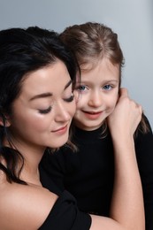 Beautiful mother with little daughter on grey background