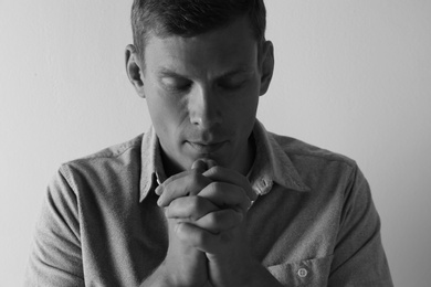 Photo of Man with hands clasped together for prayer on light background. Black and white effect