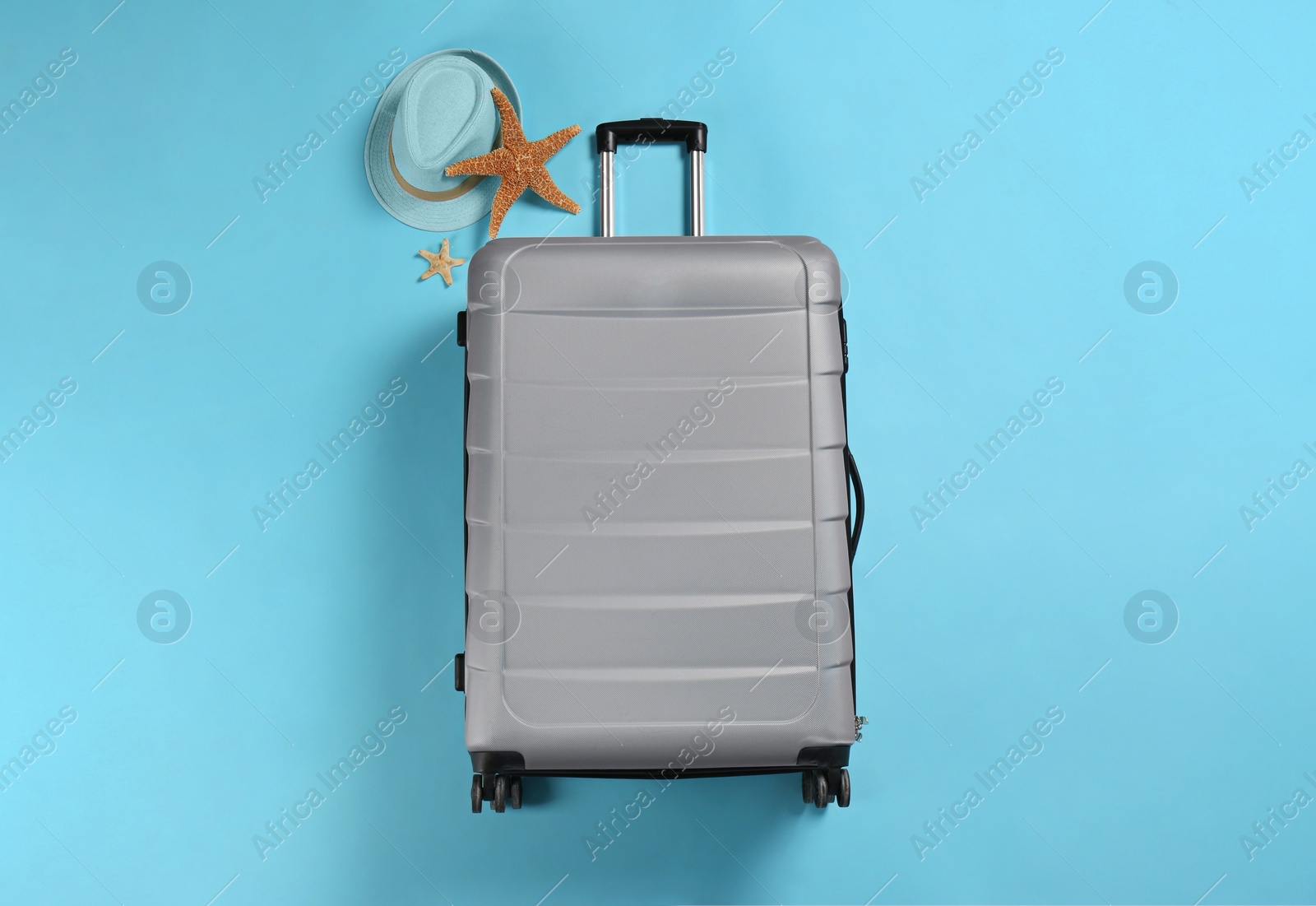 Photo of Stylish suitcase, sea stars and hat on color background, top view