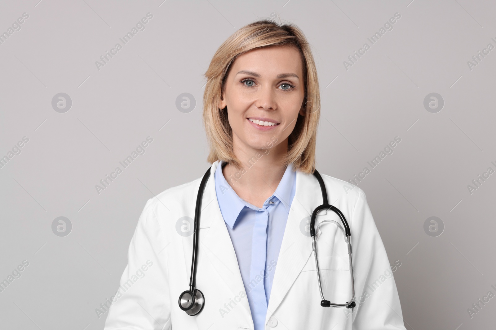 Photo of Portrait of smiling doctor on grey background