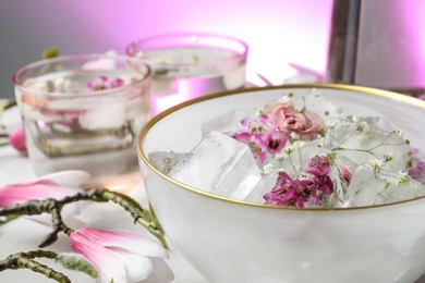 Bowl of floral ice cubes on table, closeup. Space for text