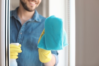 Man in casual clothes washing window glass at home