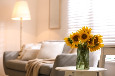 Photo of Beautiful bouquet of sunflowers in vase on white table indoors. Space for text