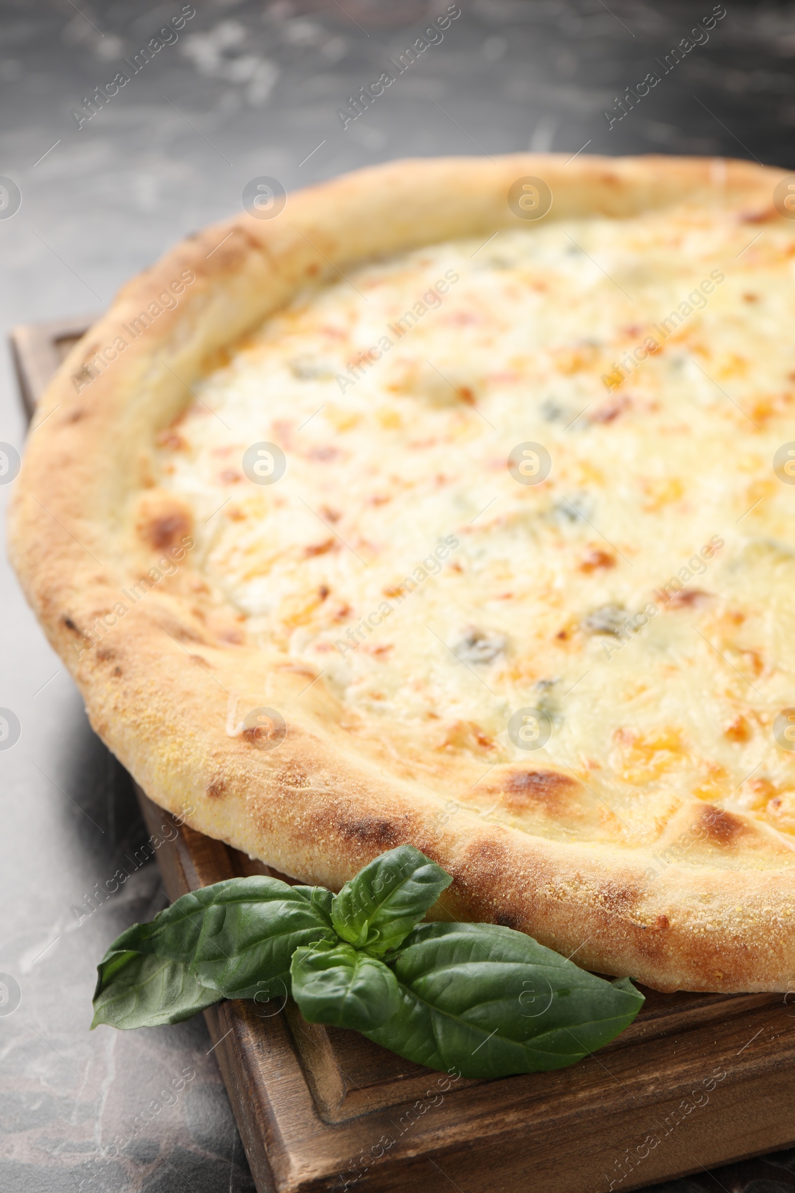 Photo of Delicious cheese pizza and basil on black marble table, closeup