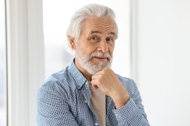 Photo of Portrait of happy grandpa with grey hair near window indoors