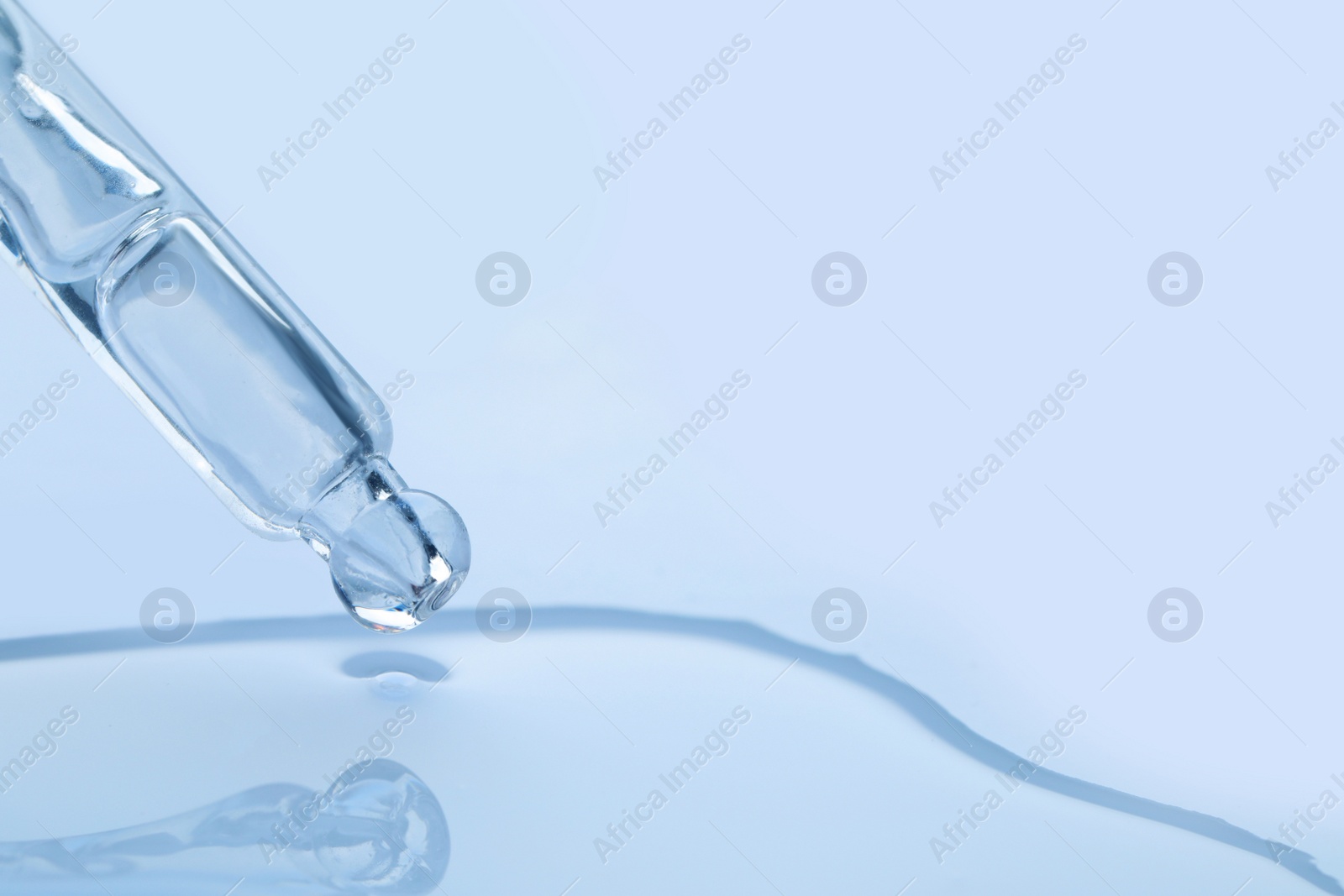 Photo of Dripping face serum from pipette on white background, closeup. Space for text