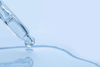 Photo of Dripping face serum from pipette on white background, closeup. Space for text