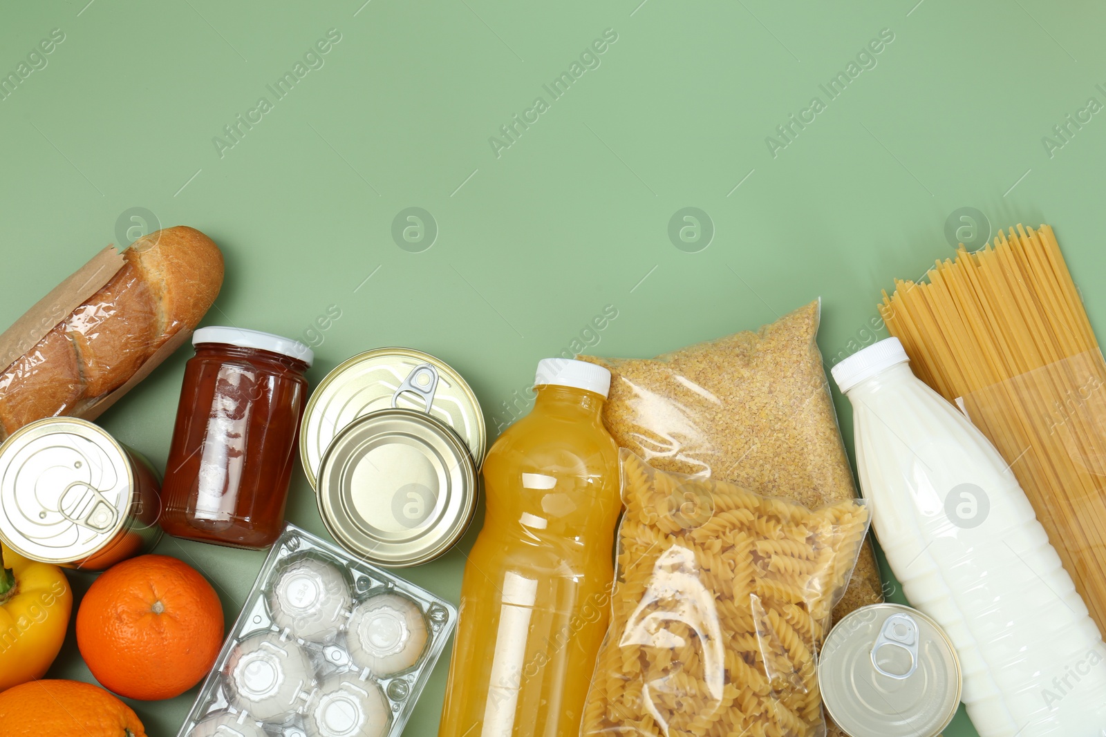 Photo of Humanitarian aid. Different food products for donation on green background, flat lay. Space for text