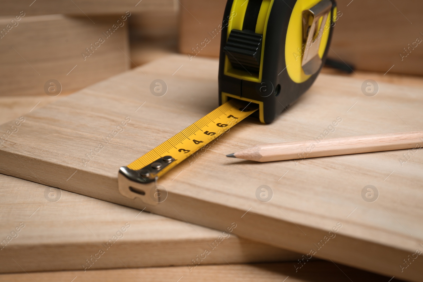 Photo of Tape measure and pencil on wooden surface, closeup