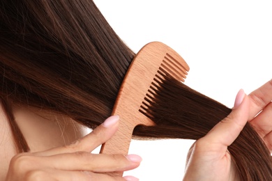 Young woman with wooden hair comb on white background, closeup