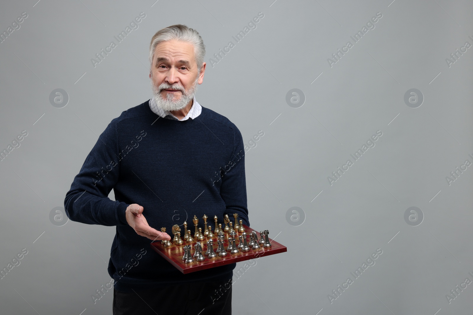 Photo of Man with chessboard and game pieces on light gray background, space for text