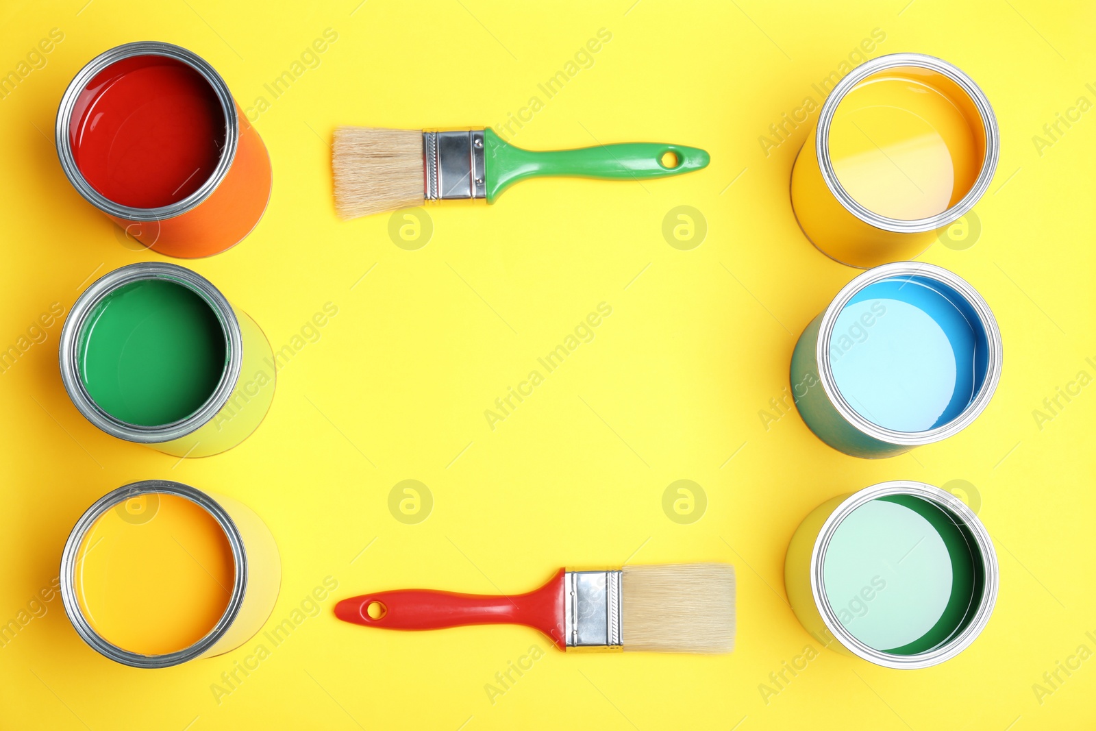 Photo of Flat lay composition with paint cans and brushes on yellow background. Space for text