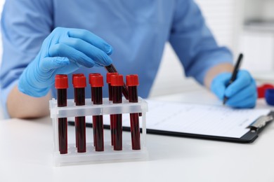 Laboratory testing. Doctor with blood samples in tubes at white table indoors