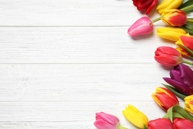 Beautiful spring tulips on white wooden table, flat lay. Space for text