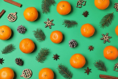 Flat lay composition with ripe tangerines, fir branches and Christmas decor on green background