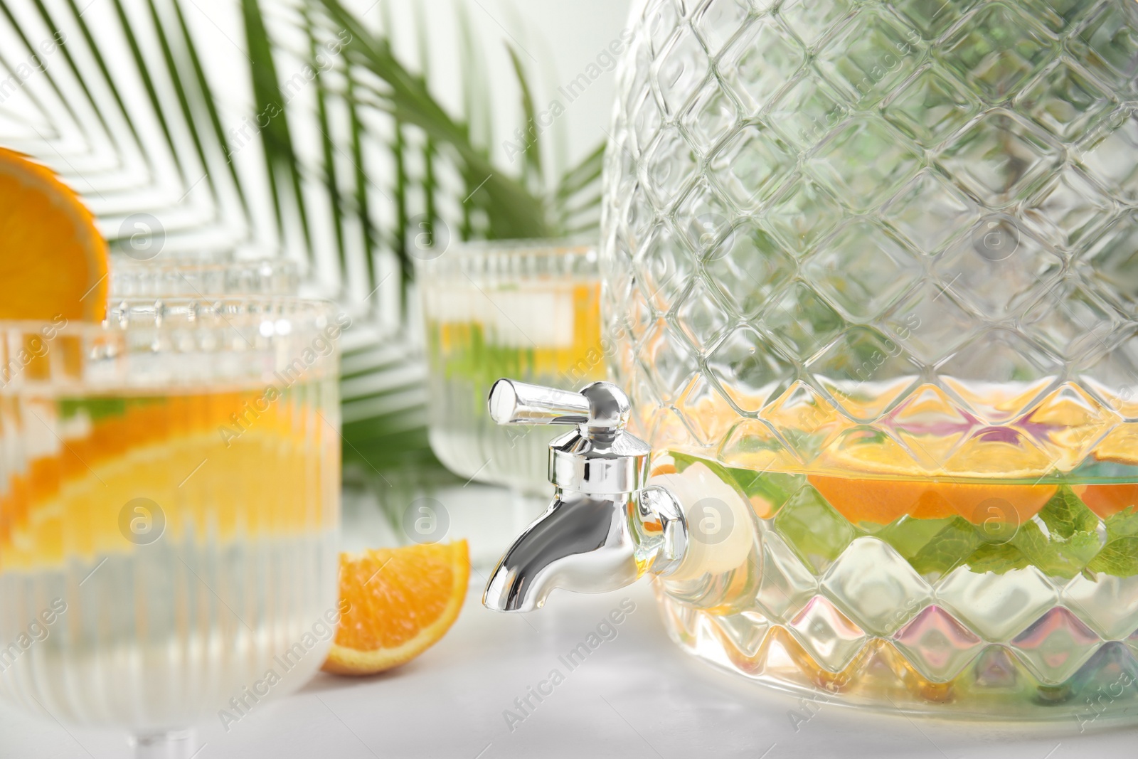 Photo of Beverage dispenser with delicious refreshing drink on white table, closeup