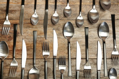 Forks, knives and spoons on wooden table, top view