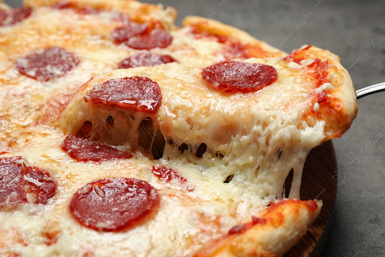 Photo of Taking slice of tasty pepperoni pizza on table, closeup