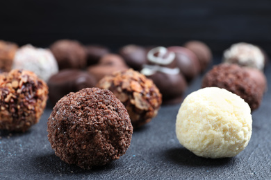 Different tasty chocolate candies on black table, closeup