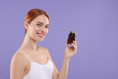 Happy young woman with bottle of pills on purple background, space for text. Weight loss