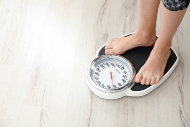 Photo of Woman measuring her weight using scales on wooden floor. Healthy diet