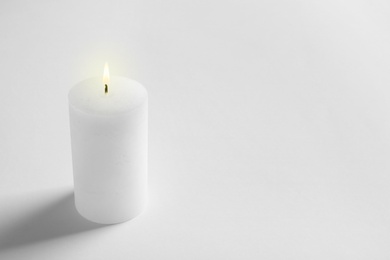 Photo of Pillar wax candle burning on white background