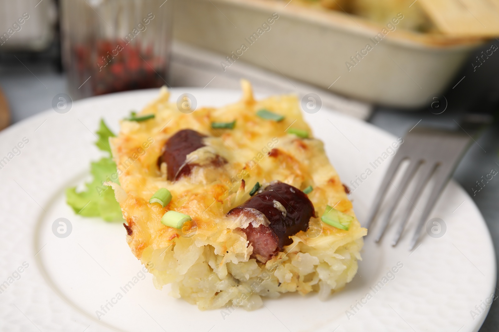 Photo of Tasty sausage casserole with green onions served on table, closeup