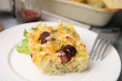 Photo of Tasty sausage casserole with green onions served on table, closeup