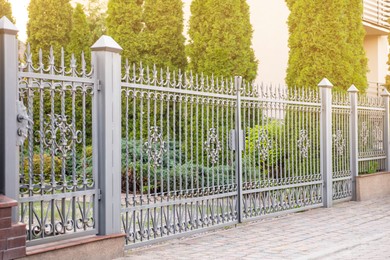 Photo of Trees behind beautiful iron fence near pathway outdoors