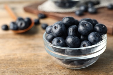 Photo of Bowl of fresh acai berries on wooden table, closeup view. Space for text