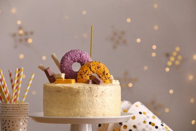 Delicious cake decorated with sweets and festive items against blurred lights