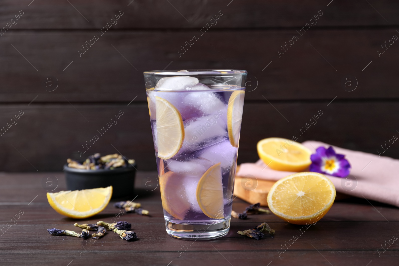 Photo of Organic blue Anchan with lemon in glass on wooden table. Herbal tea